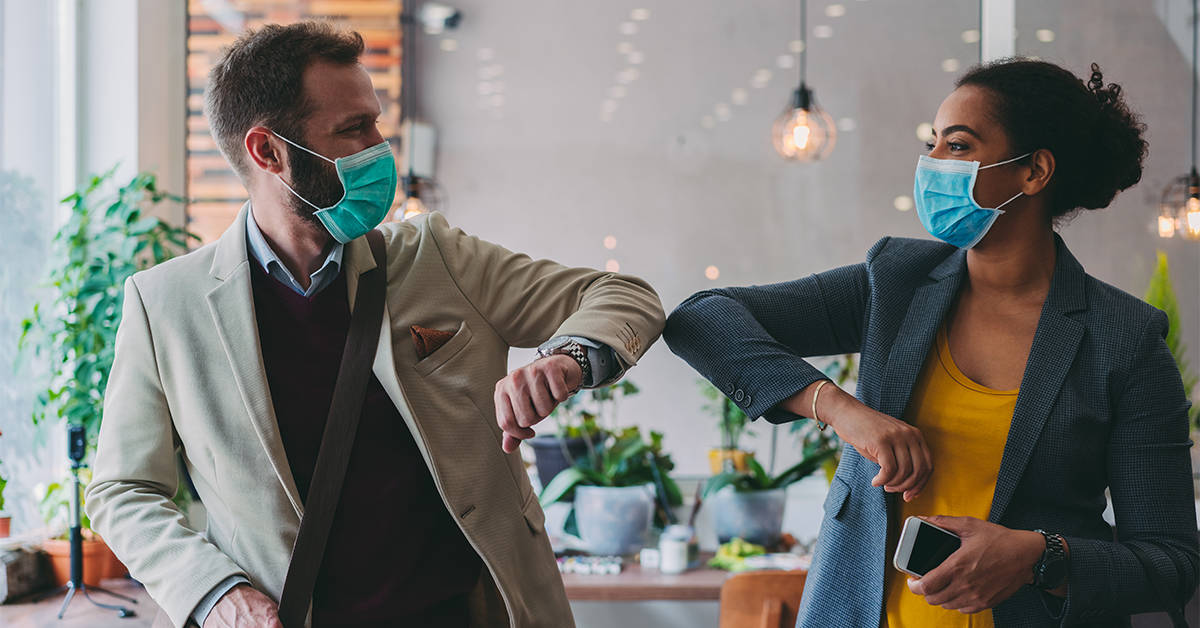 Colleagues in the office practicing alternative greeting to avoid handshakes during COVID-19 pandemic